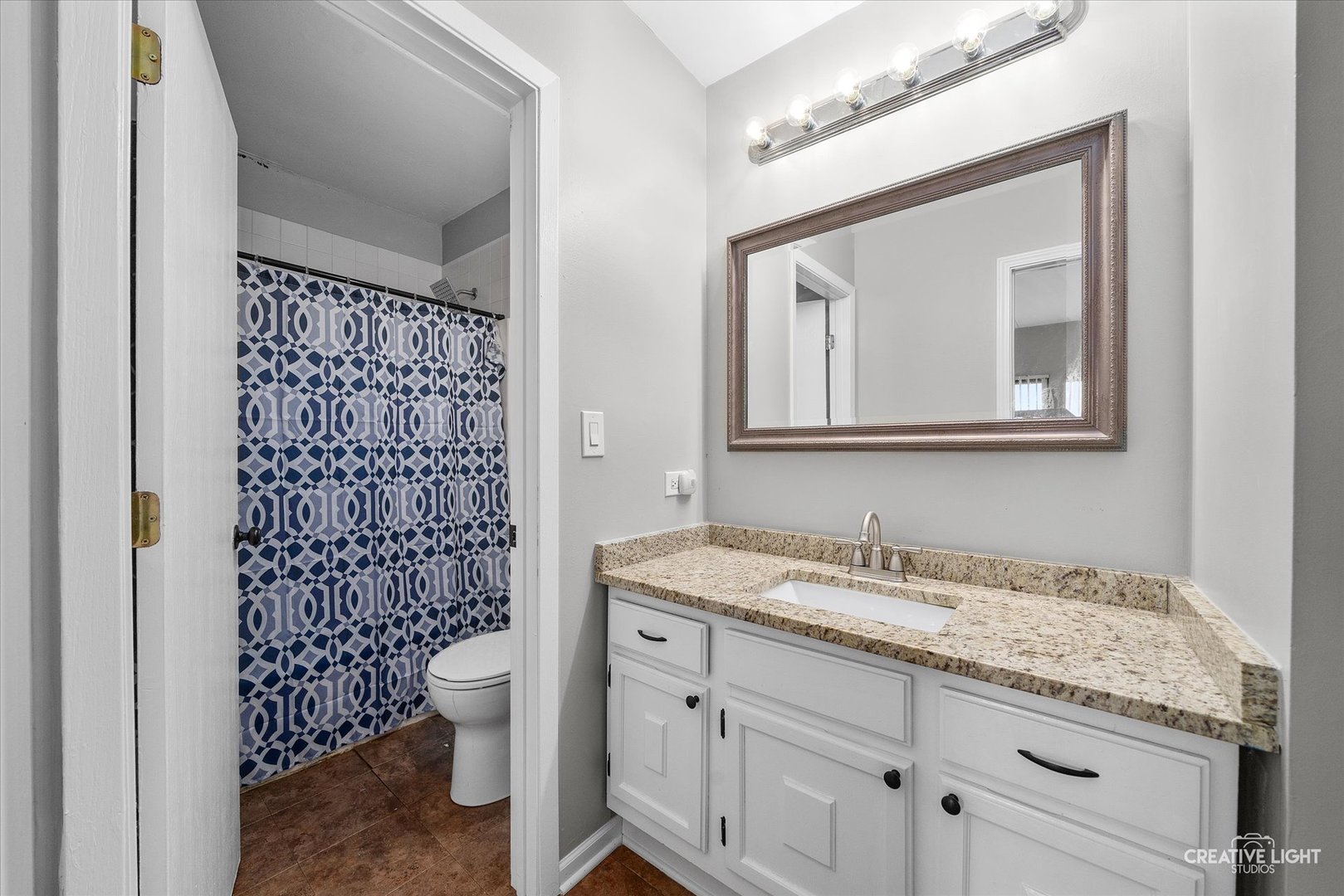 1807 Kenneth Circle Elgin, IL 60120 - Photo 9 of 16 a bathroom with a granite countertop toilet a sink a mirror a window and a shower
