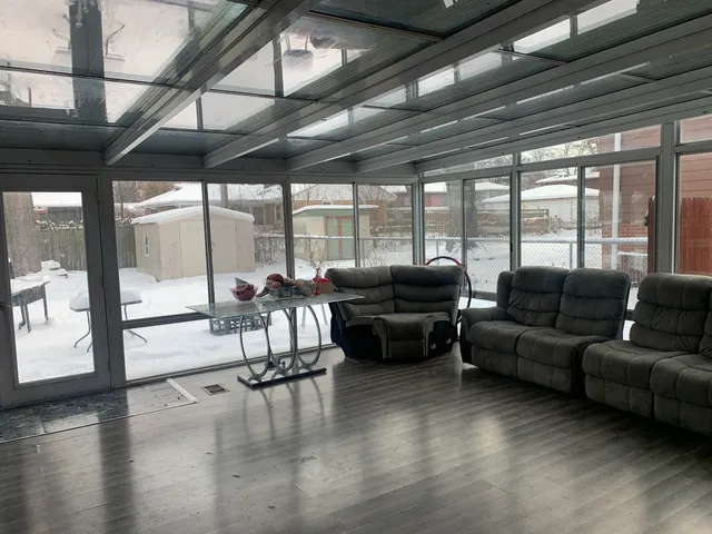 a living room with furniture wooden floor and floor to ceiling windows