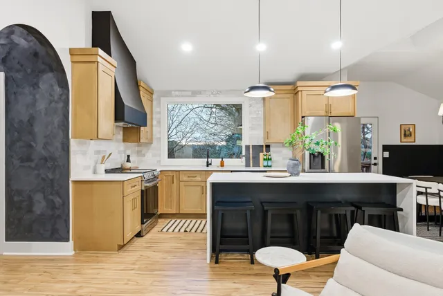 a kitchen with kitchen island a dining table chairs and white cabinets