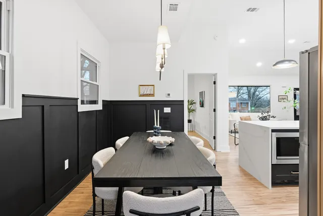 a kitchen with stainless steel appliances granite countertop a sink a stove a refrigerator and a dining table with wooden floor