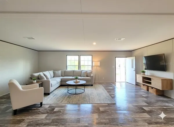 a view of an empty room with a window and wooden floor