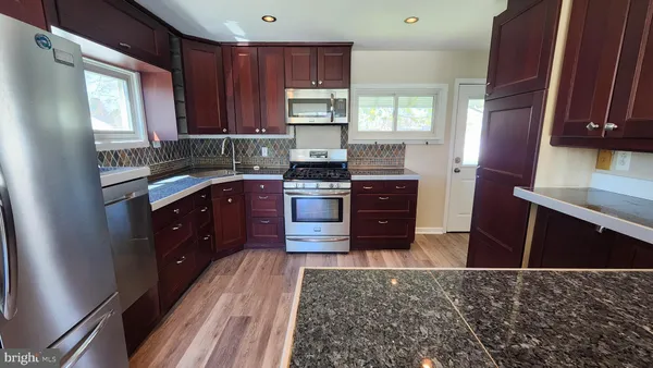 a kitchen with stainless steel appliances granite countertop a stove a sink dishwasher a refrigerator and wooden cabinets