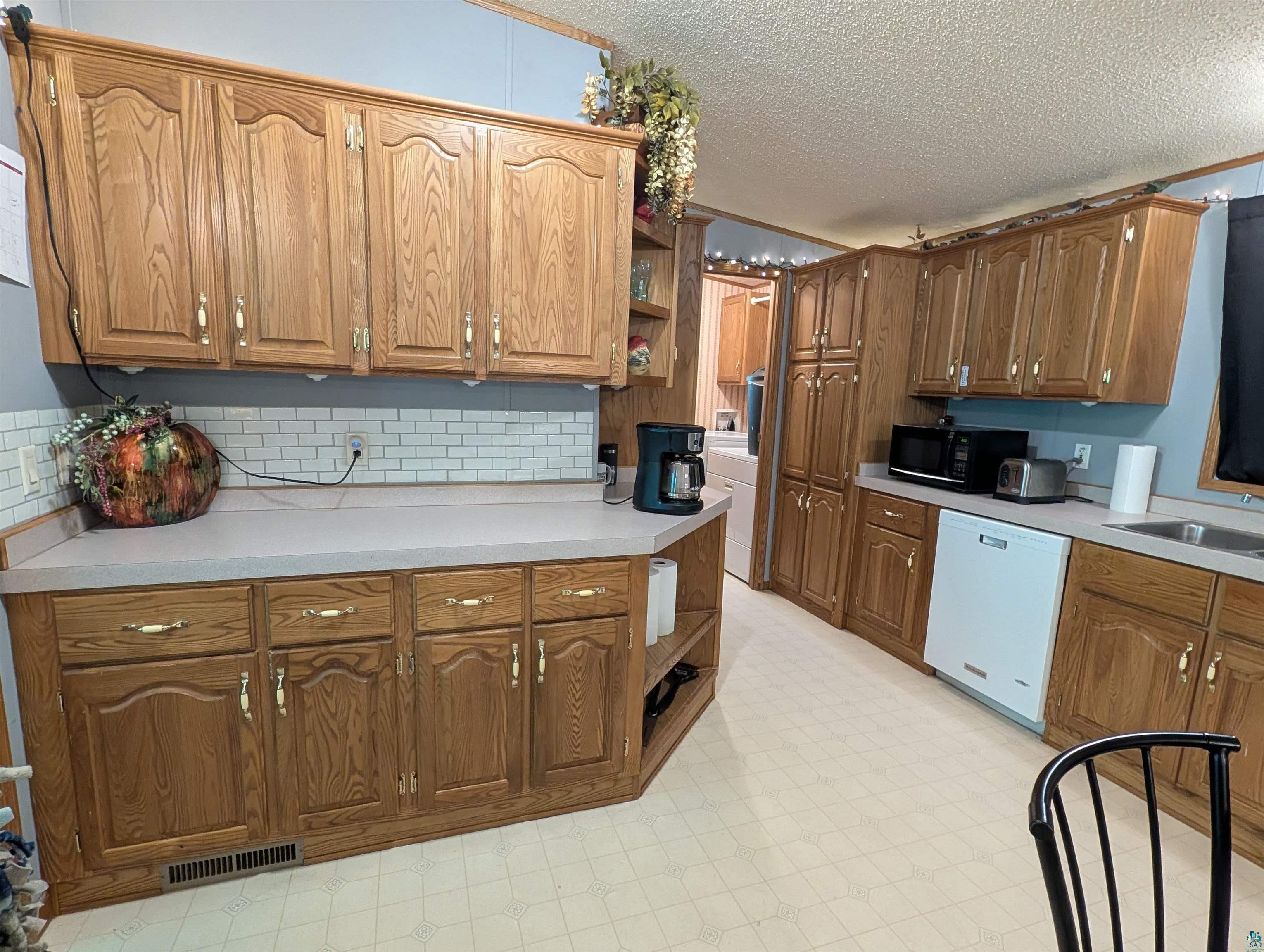 3945 Maple Street Kettle River, MN 55757 - Photo 7 of 41 Kitchen featuring extensive wood cabinetry, light-toned countertops, and a white subway tile backsplash