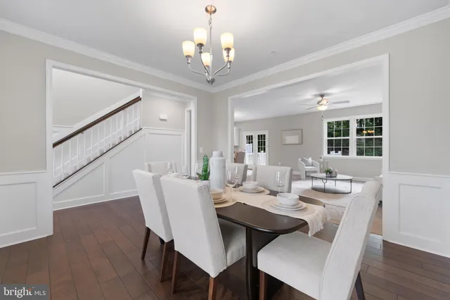 a dining room with wooden floor a chandelier a wooden table and chairs