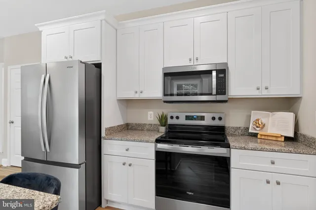 a kitchen with granite countertop white cabinets and stainless steel appliances