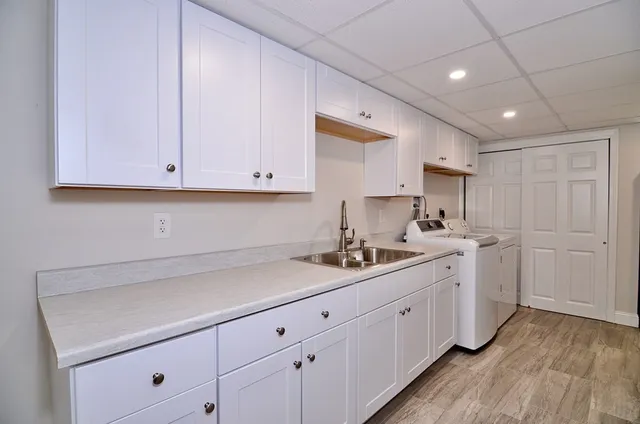 a kitchen with a sink dishwasher and cabinets with wooden floor