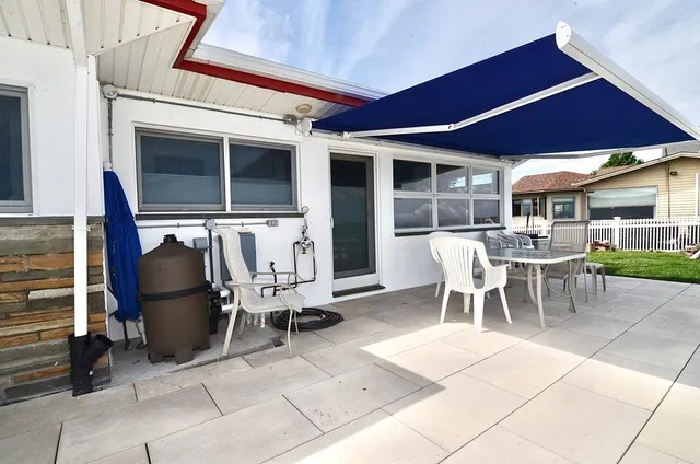 a patio with a table and chairs and potted plants