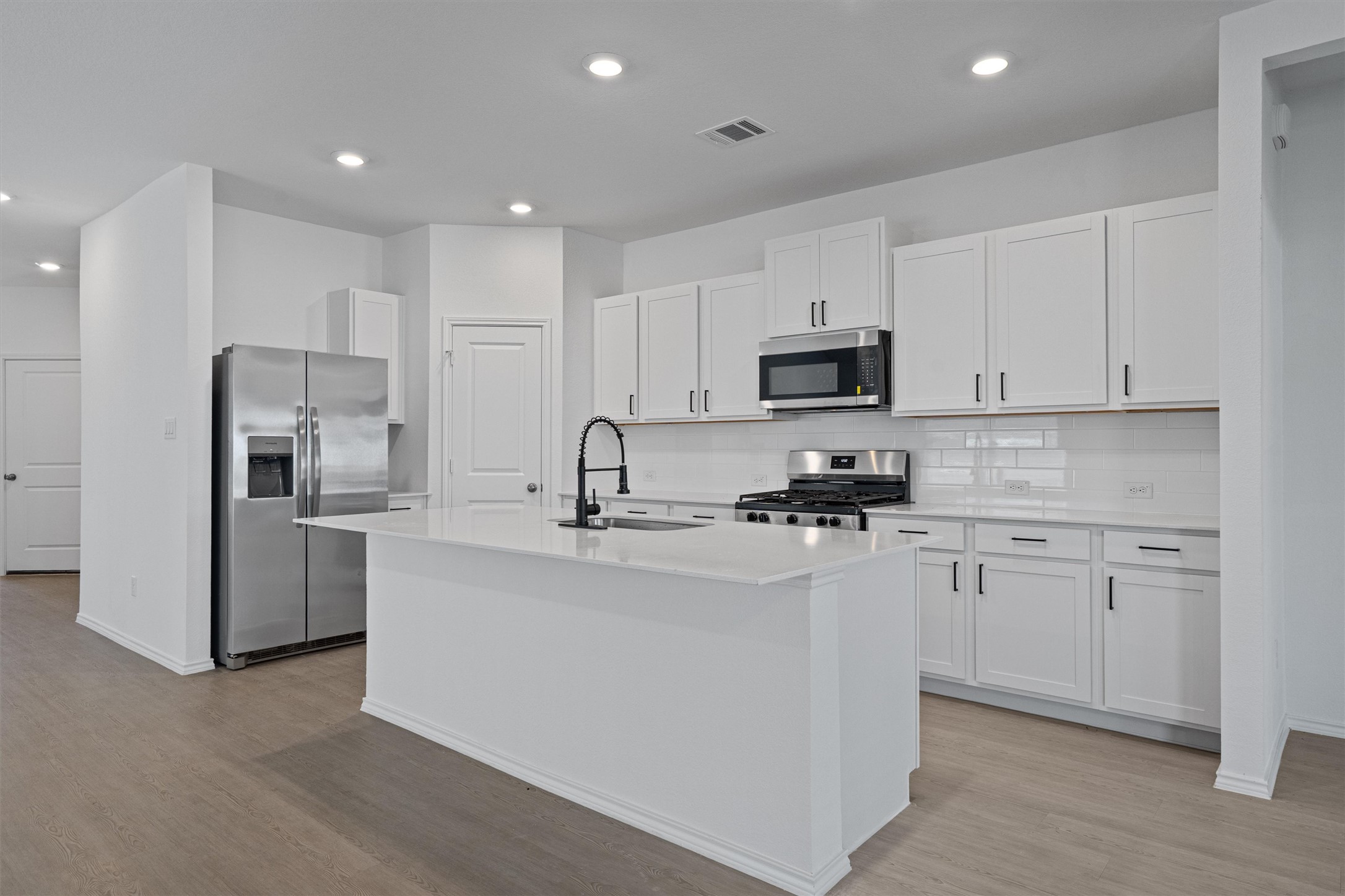 3305 Everett Kyle, TX 78640 - Photo 2 of 21 Kitchen with stainless steel appliances, white cabinets, recessed lighting, an island with sink, and light wood-style flooring