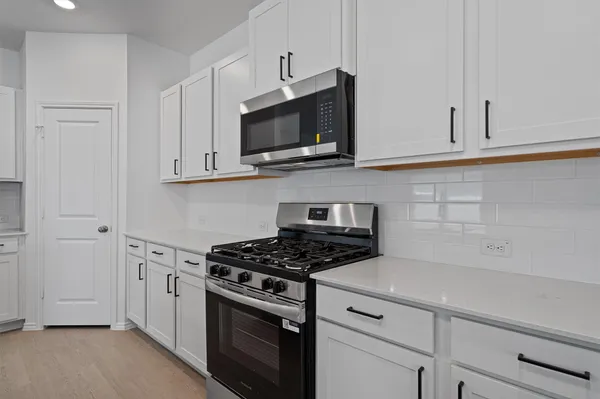 a kitchen with white cabinets and stainless steel appliances