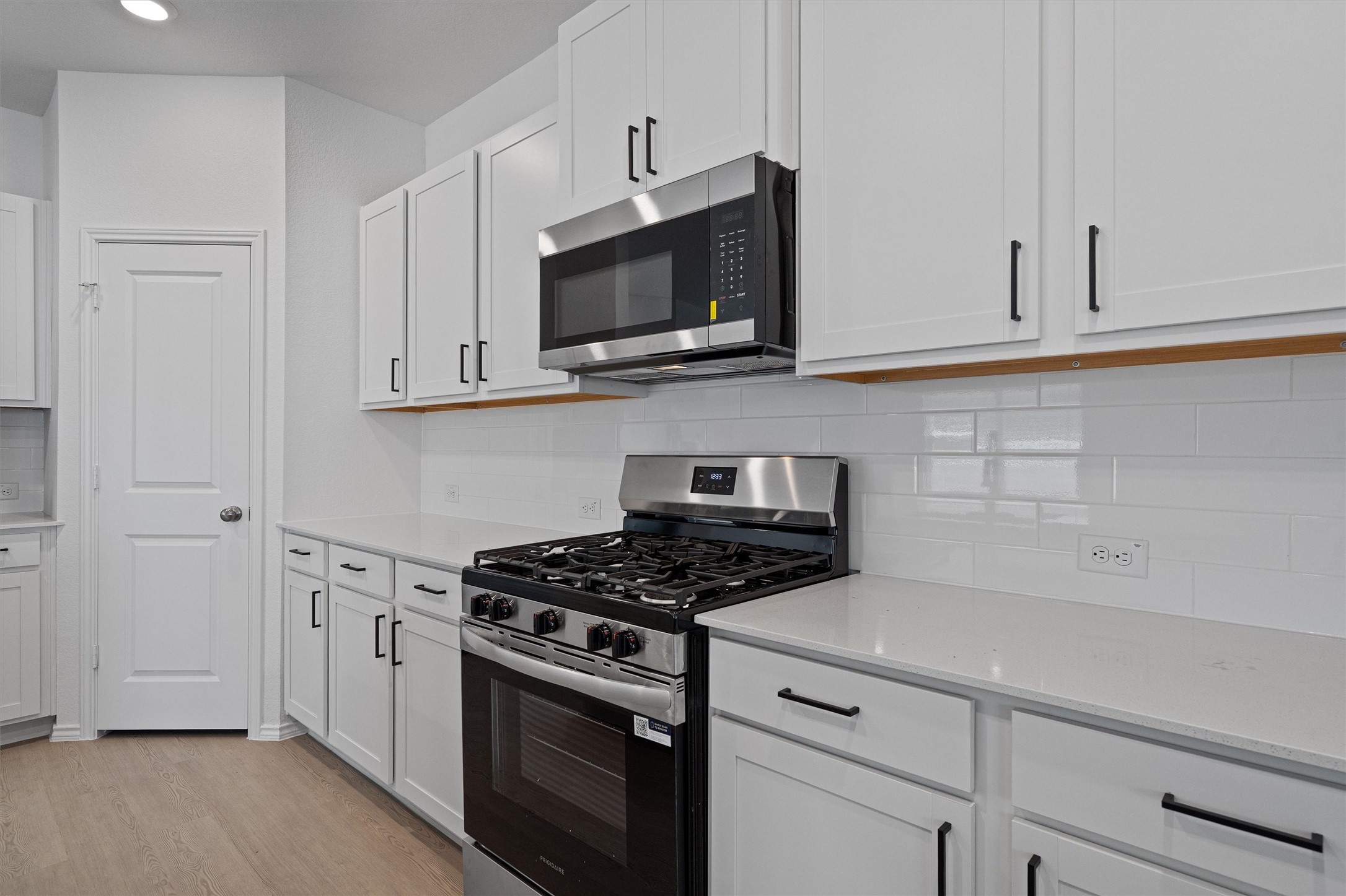 3305 Everett Kyle, TX 78640 - Photo 3 of 21 Kitchen with stainless steel appliances, tasteful backsplash, white cabinets, and light wood-style floors