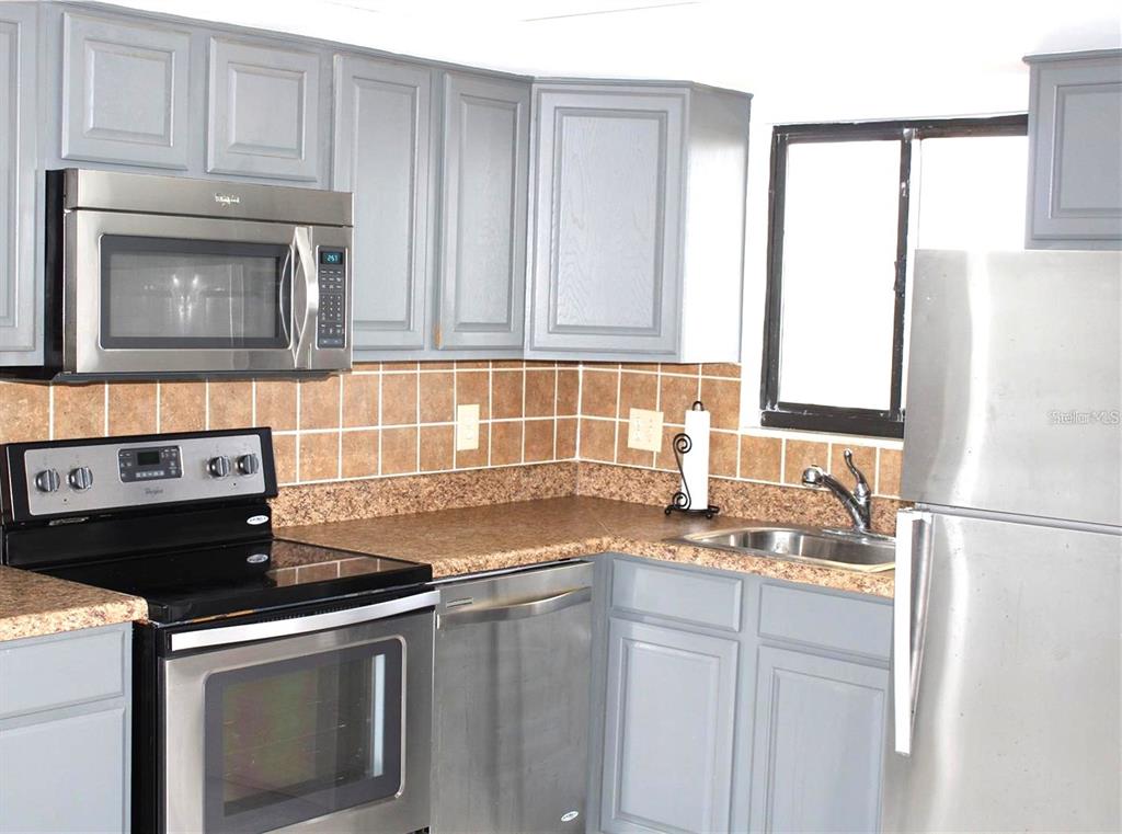 6009 Sea Ranch Drive, Unit 705 Hudson, FL 34667 - Photo 5 of 43 a kitchen with granite countertop a sink stove and cabinets