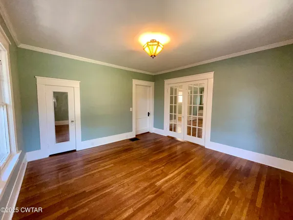 a view of an empty room with wooden floor and a window