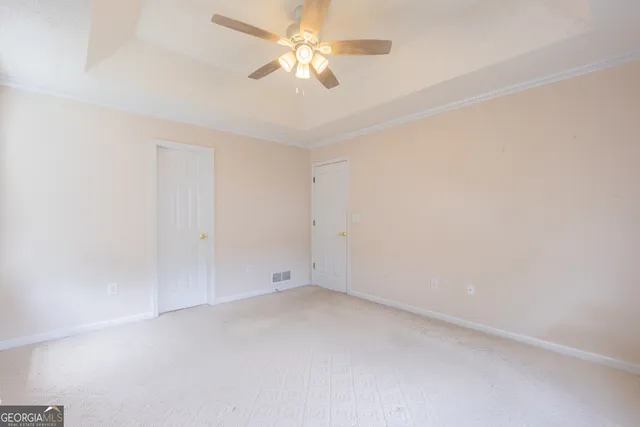 an empty room with a fan & a ceiling fan