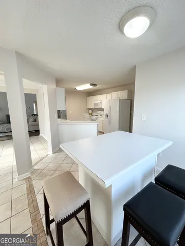 a large white kitchen with a sink and dishwasher a refrigerator with white cabinets