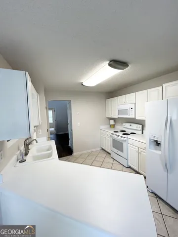a kitchen with a sink a refrigerator and cabinets