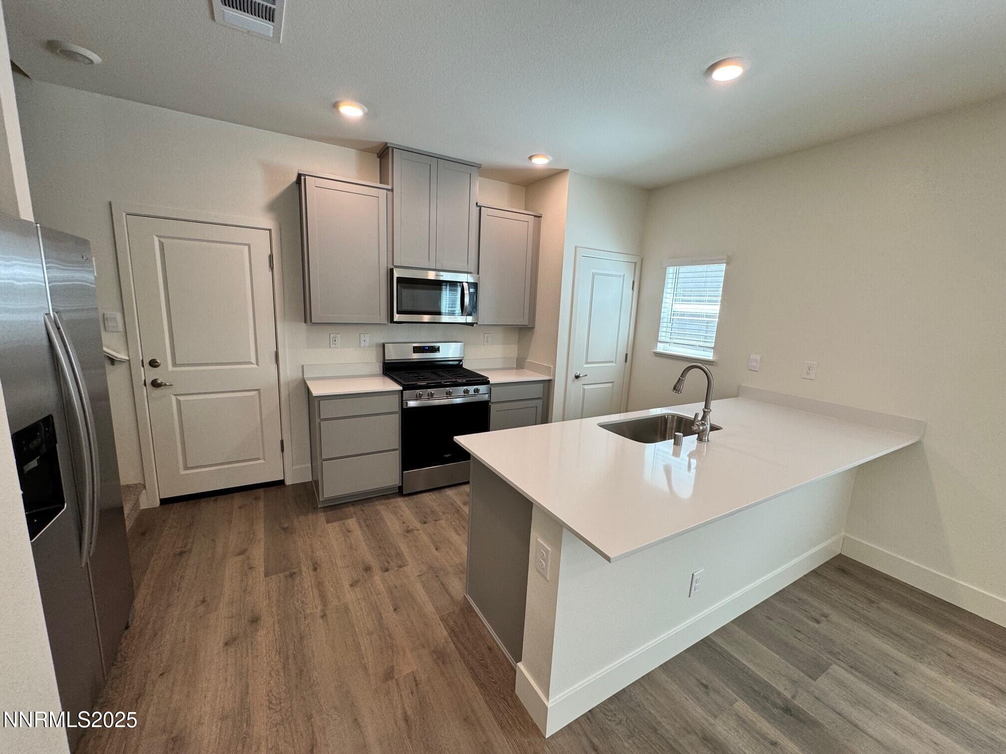 1615 Prancer Street, Unit LOT #53 Reno, NV 89523 - Photo 4 of 34 a kitchen with stainless steel appliances a sink dishwasher a refrigerator and a stove with wooden floor