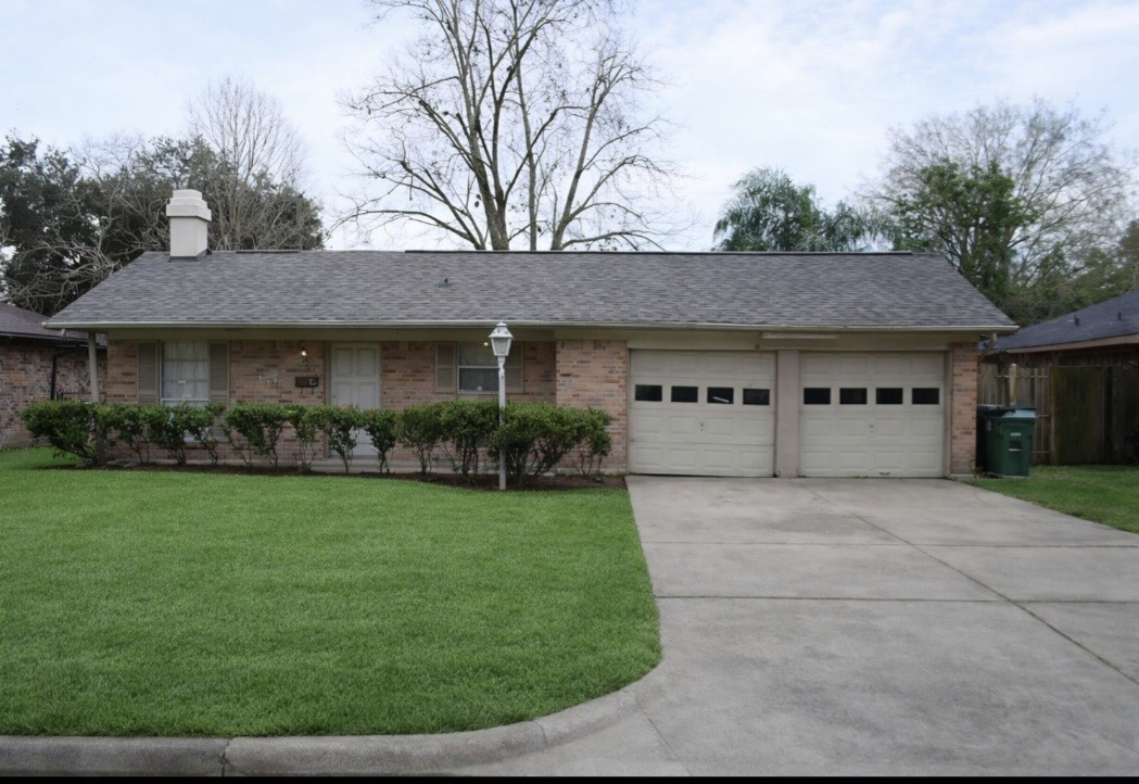 a view of house in front of a big yard with large trees