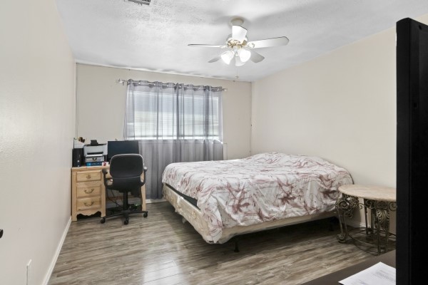 9702 Tiltree Street Houston, TX 77075 - Photo 14 of 24 a bedroom with a bed a chair and a chandelier