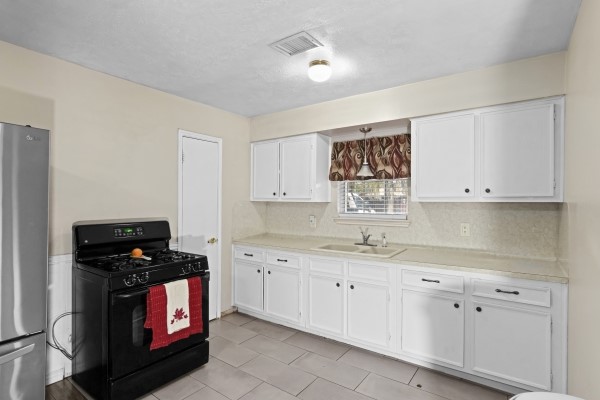 9702 Tiltree Street Houston, TX 77075 - Photo 7 of 24 a kitchen with white cabinets a stove and a refrigerator