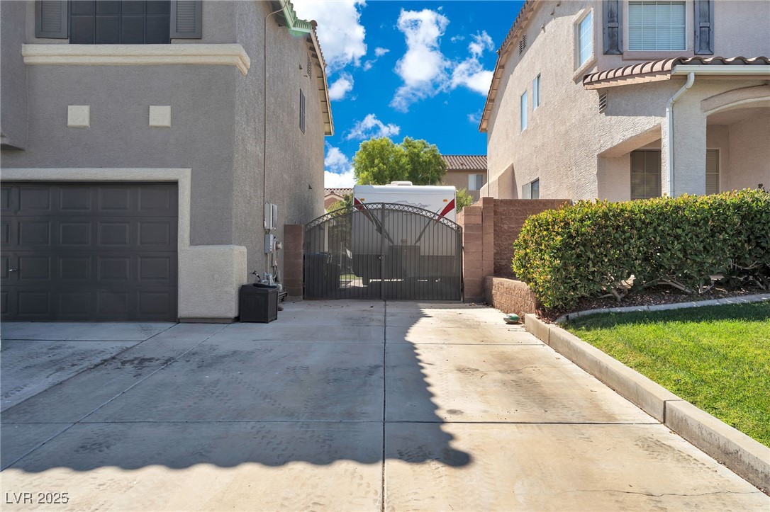 View of property exterior with a gate, stucco siding, a tiled roof, and driveway