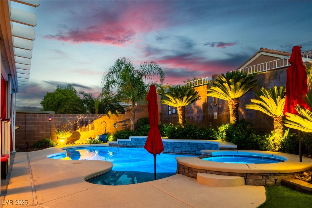 View of swimming pool with an in-ground hot tub, a fenced backyard, and a patio