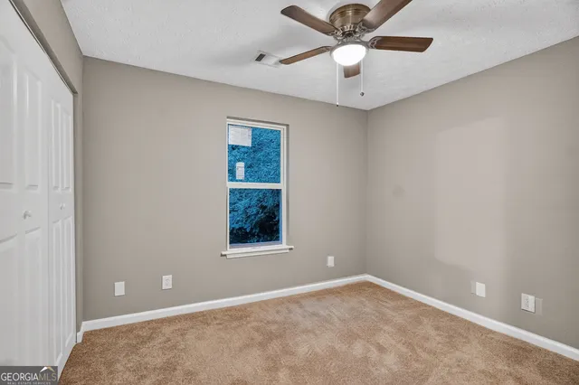 an empty room with windows and fan