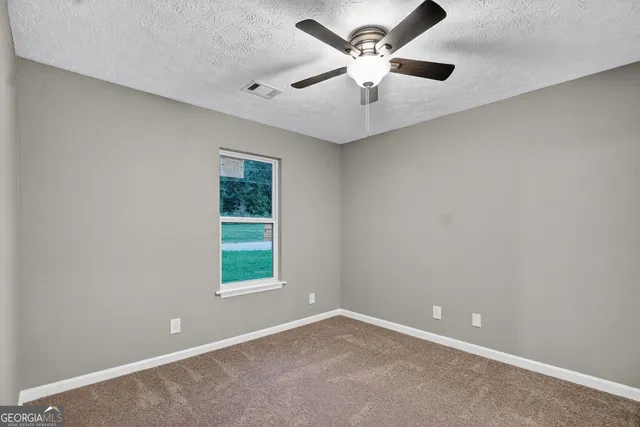 an empty room with windows and fan