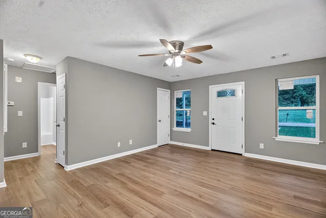 a view of an empty room with a window and wooden floor