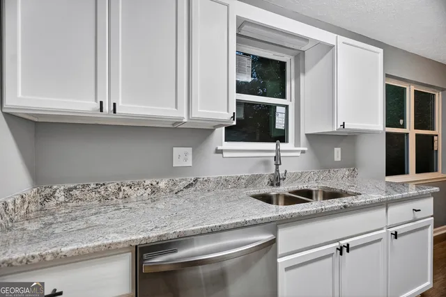 a kitchen with granite countertop white cabinets and a sink