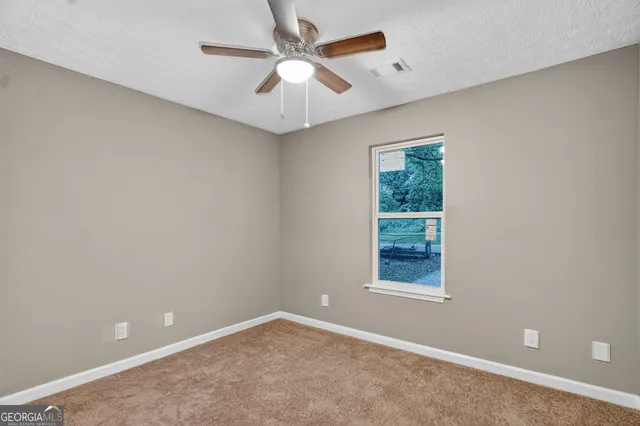 an empty room with a window and a ceiling fan