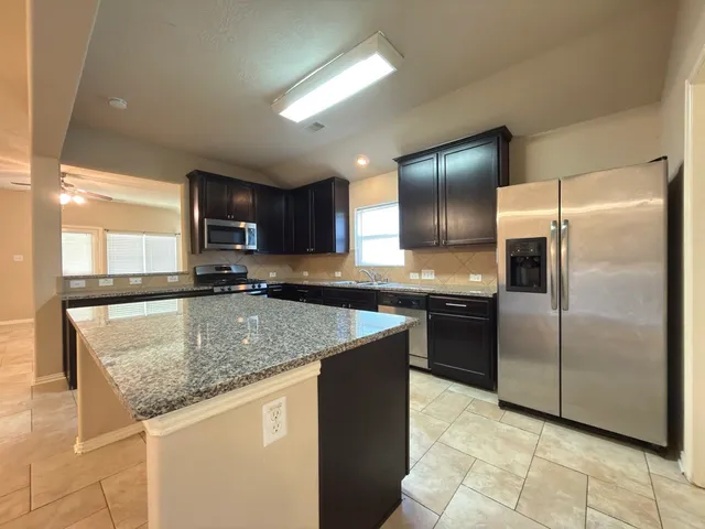 a kitchen with stainless steel appliances granite countertop a sink a stove and a refrigerator