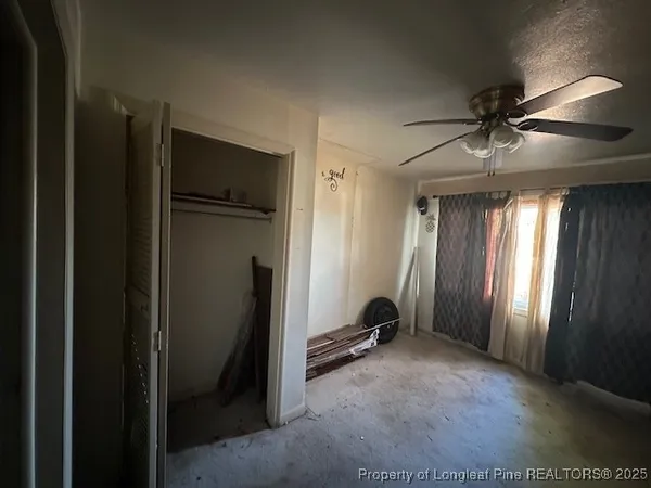 a view of a livingroom with a staircase a ceiling fan and closet area
