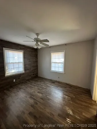 an empty room with windows and fan