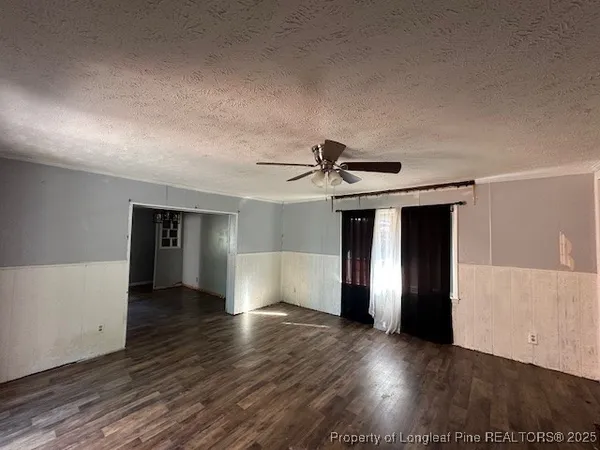 a view of a livingroom with wooden floor and a ceiling fan