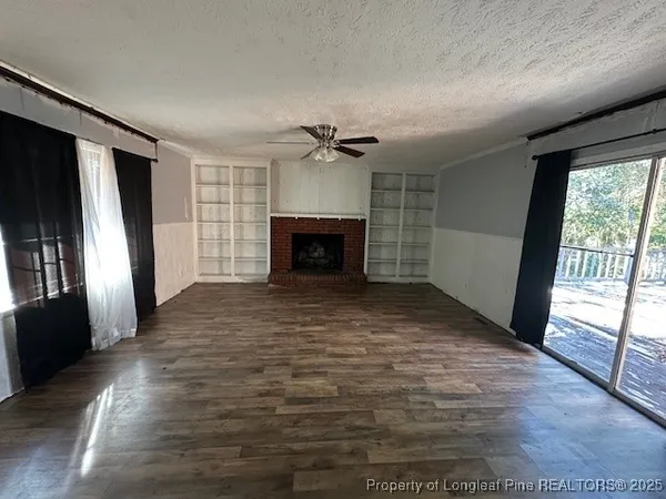 an empty room with windows fireplace and a wooden floor