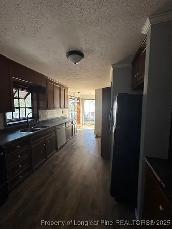 a kitchen with stainless steel appliances granite countertop a refrigerator a sink dishwasher a stove and a dining table with wooden floor