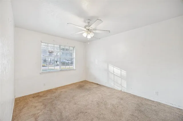 an empty room with a window and ceiling fan