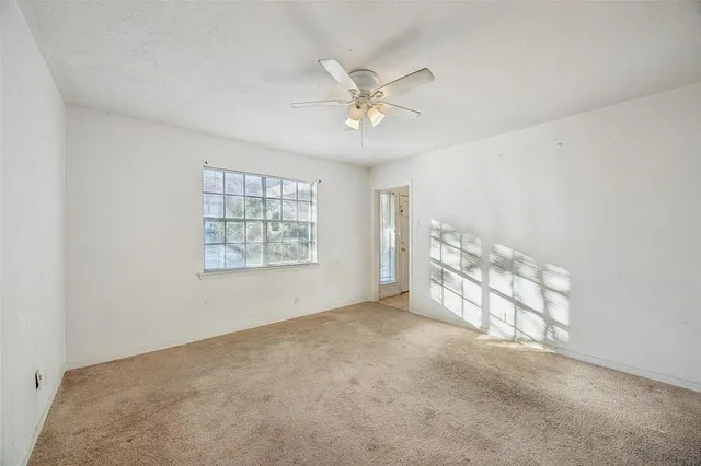 an empty room with windows and fan