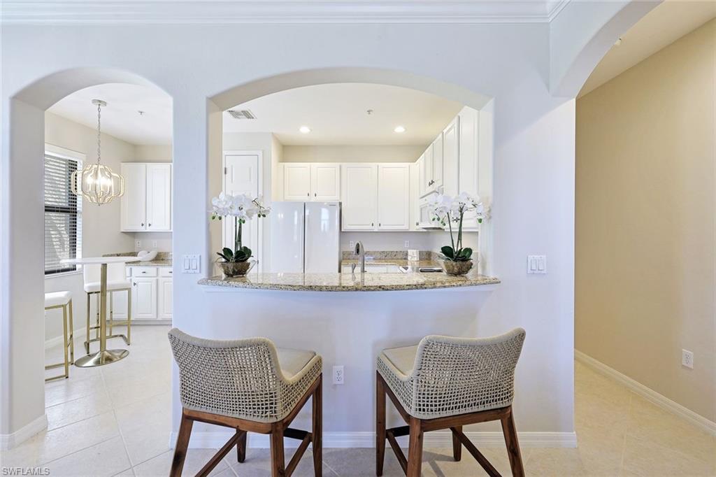 1423 Santiago Circle, Unit 1702 Naples, FL 34113 - Photo 7 of 46 a kitchen with stainless steel appliances granite countertop a dining table chairs and white cabinets