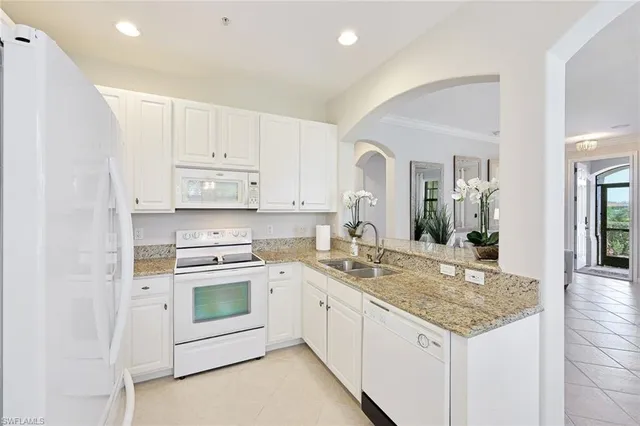 a kitchen with granite countertop white cabinets and white appliances