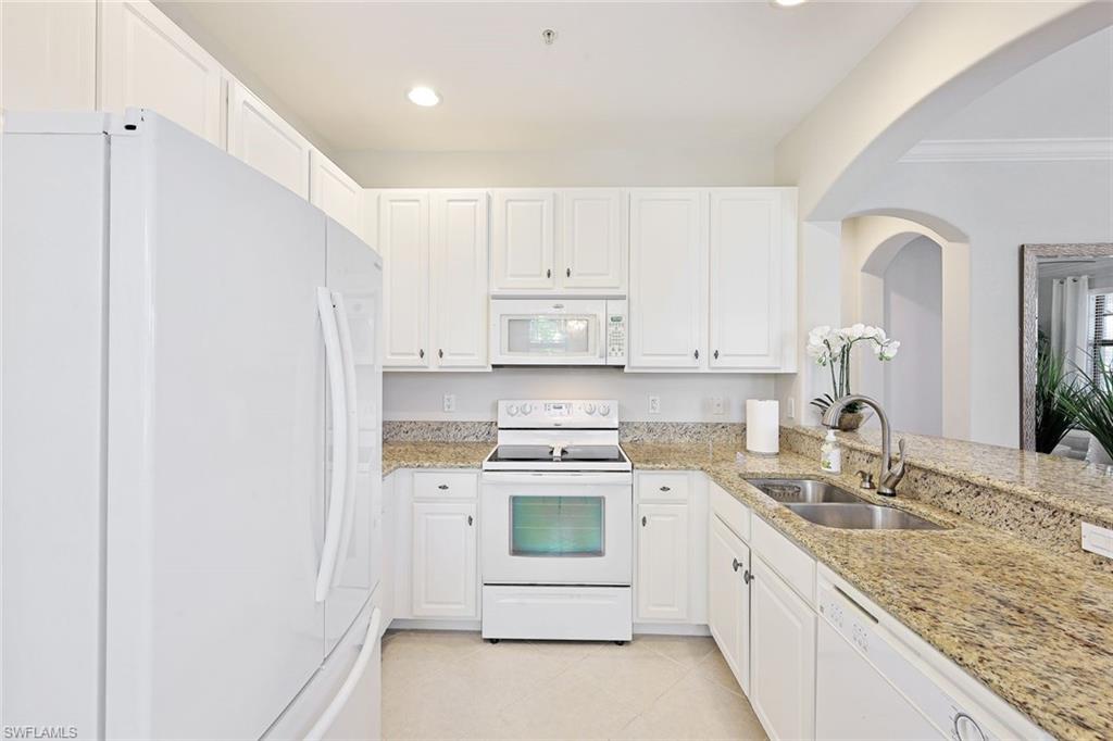 1423 Santiago Circle, Unit 1702 Naples, FL 34113 - Photo 10 of 46 a kitchen with white cabinets and white appliances