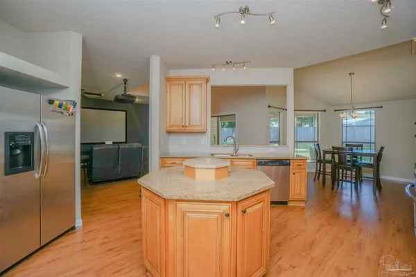 a kitchen with stainless steel appliances granite countertop wooden cabinets a sink dishwasher a stove and a refrigerator with wooden floor