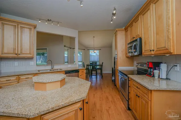 a kitchen with granite countertop wooden cabinets a stove top oven a sink and dishwasher