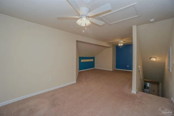 an empty room with a chandelier fan and windows