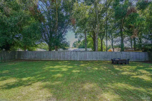 a view of backyard with wooden fence and a large tree