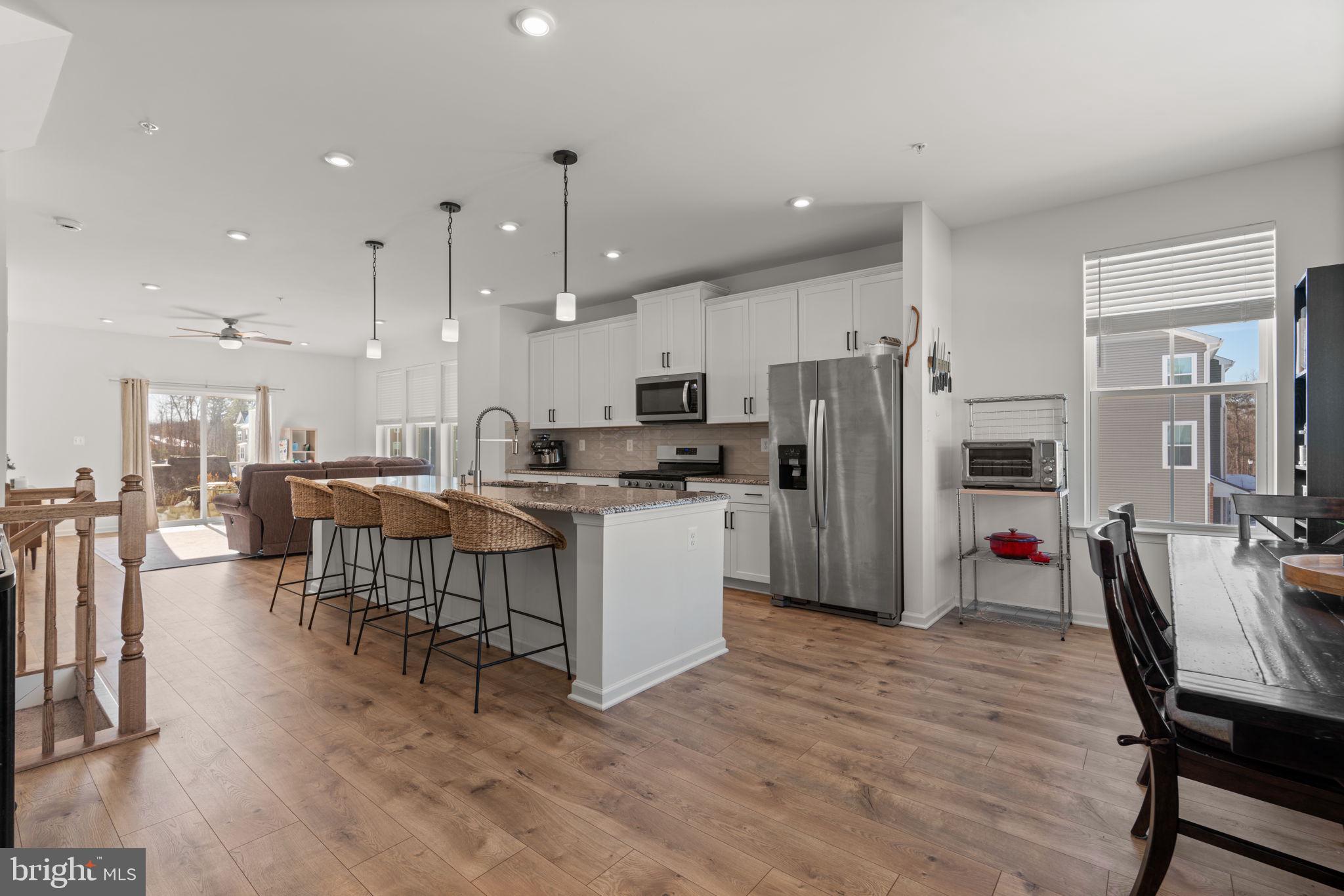 1605 Aster Lane Hanover, MD 21076 - Photo 15 of 44 a kitchen with stainless steel appliances kitchen island granite countertop a refrigerator a stove a sink a dining table and chairs with wooden floor