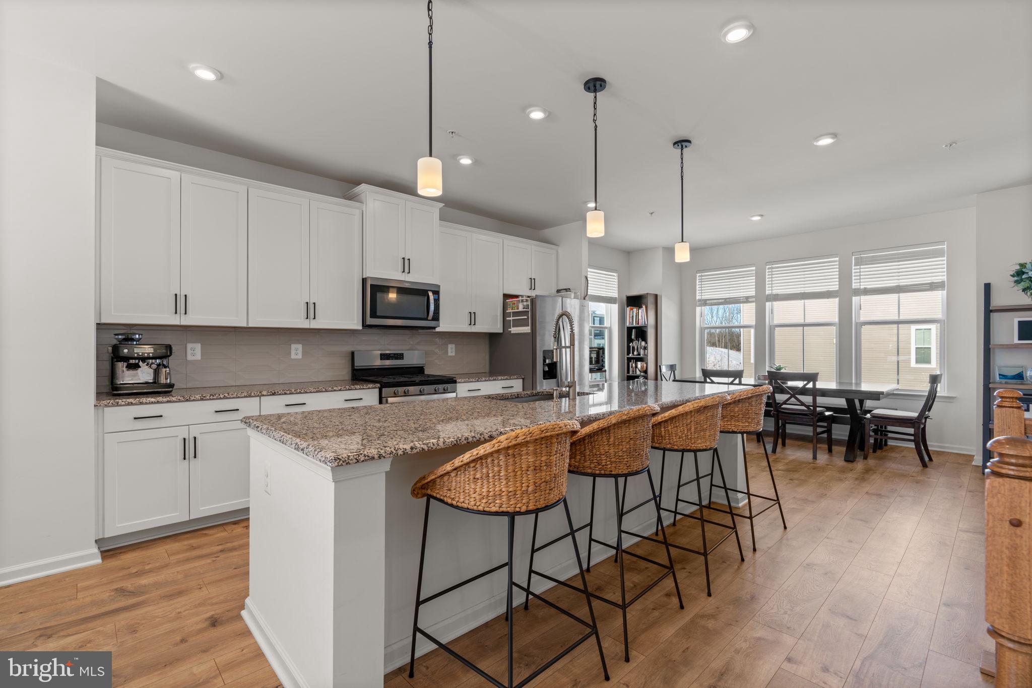 1605 Aster Lane Hanover, MD 21076 - Photo 9 of 44 a kitchen with stainless steel appliances granite countertop a stove top oven a sink a dining table and chairs with wooden floor