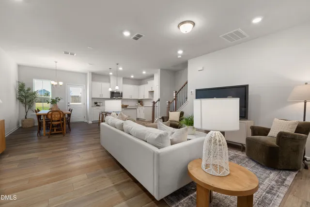 a living room with furniture and a dining table with wooden floor