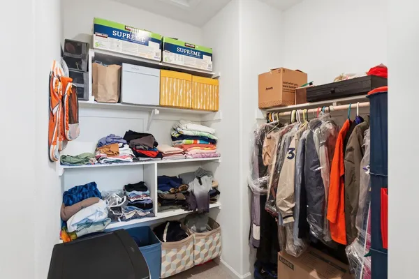 a view of walk in closet with clothes and shoes