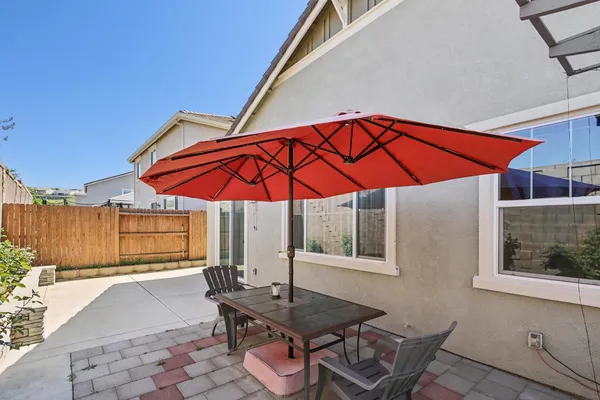 a patio with a table and chairs under an umbrella